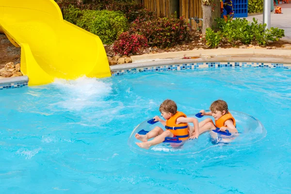 Bambini entusiasti nel parco acquatico cavalcando sullo scivolo con galleggiante — Foto Stock