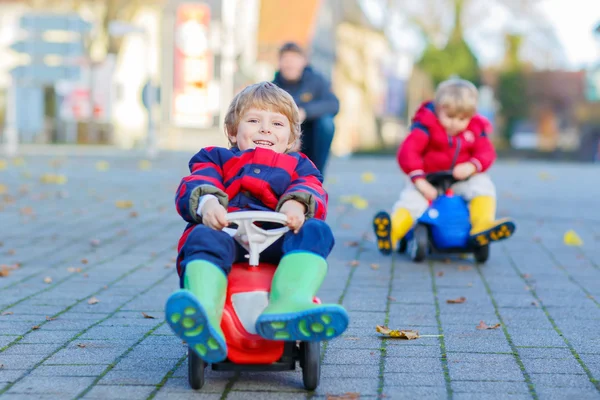 Dos niños pequeños niños y padre jugando con coches, al aire libre — Foto de Stock