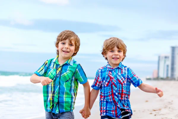 Deux petits garçons courent sur la plage de l'océan — Photo