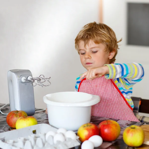 Rolig blond liten pojke baka äppelkaka inomhus — Stockfoto