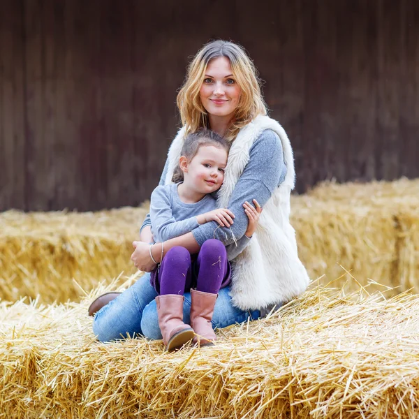 Счастливая девочка и мать веселятся с сеном на ферме — стоковое фото