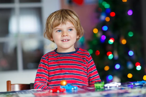 Μικρό ξανθό παιδί που παίζει με τα αυτοκίνητα και τα παιχνίδια στο σπίτι — Φωτογραφία Αρχείου