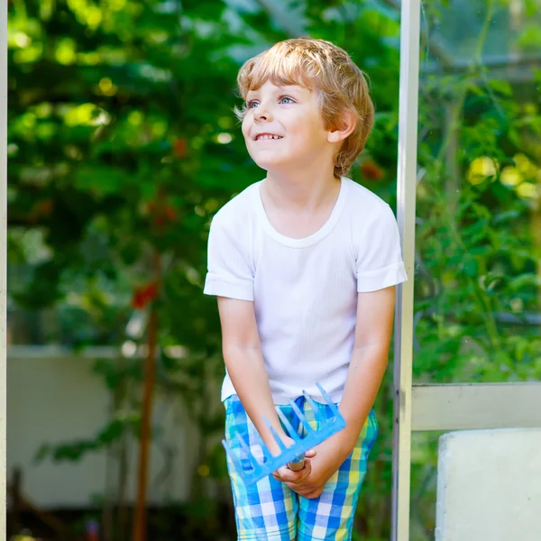 Liten unge pojke arbetar med trädgård hoe i växthus — Stockfoto