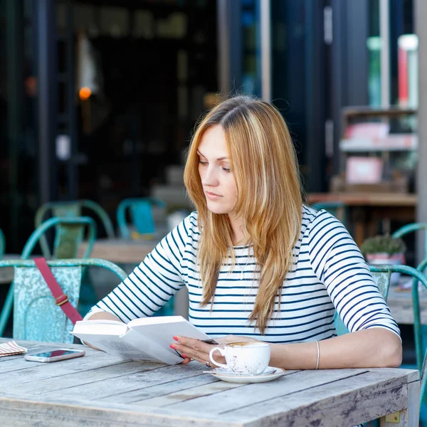 Женщина пьет кофе и читает книги в кафе — стоковое фото