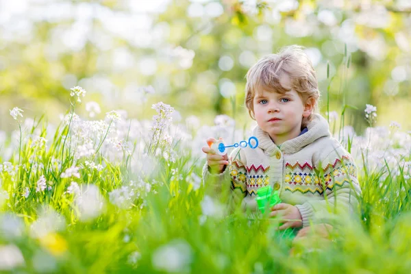 Niño pequeño en el jardín de primavera con flores en flor — Foto de Stock