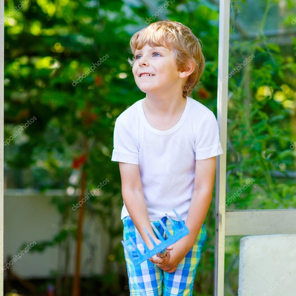 Niño pequeño trabajando con azada de jardín en invernadero — Fotos de