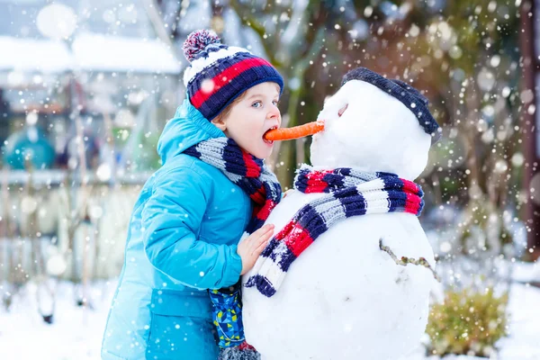 Enfant drôle garçon en vêtements colorés faire un bonhomme de neige, en plein air — Photo