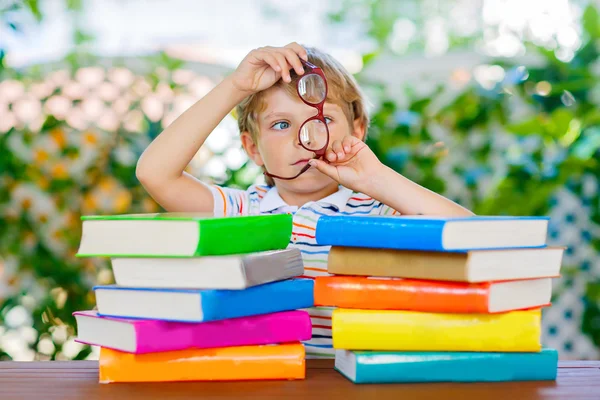 Маленький мальчик читает книги в школе — стоковое фото