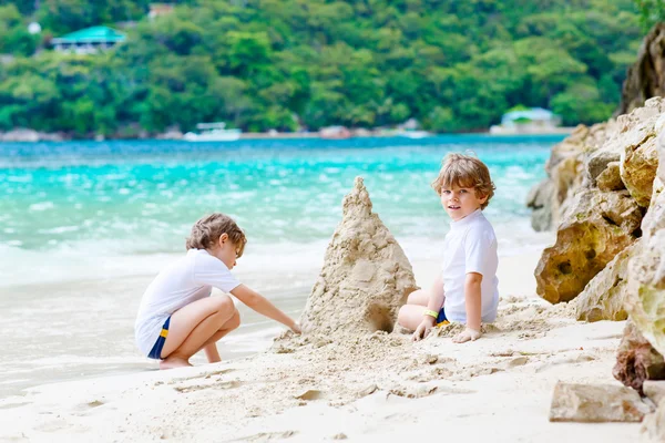 Twee jongen jongens bouwen van zandkasteel op tropisch strand — Stockfoto