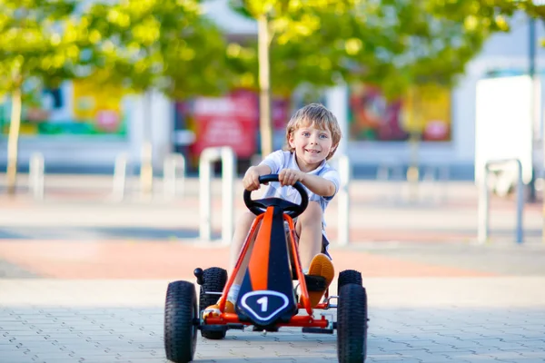 Little kid boy driving pedal race car in summer — Stock Photo, Image