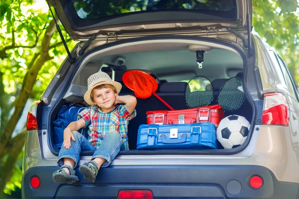 Kleiner Junge sitzt im Kofferraum des Autos, kurz bevor er in den Urlaub fährt — Stockfoto