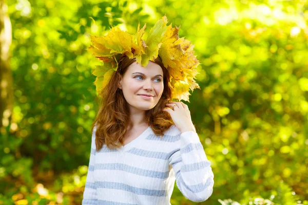 Happy young woman with autumn maple leaves garland in park. — Stock Photo, Image