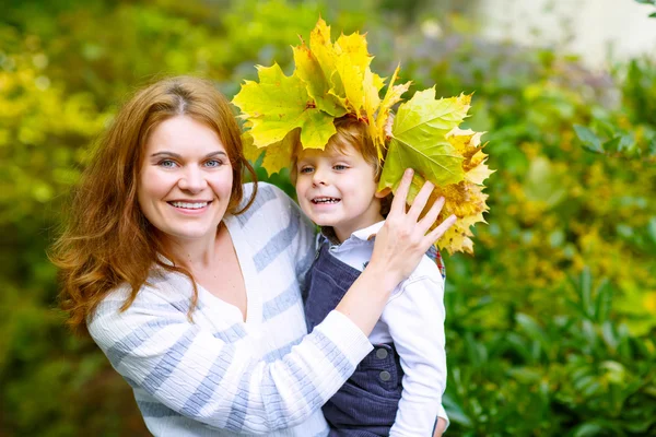 Mother with maple leaf wreath holding little toddler boy in autu — Stock Photo, Image