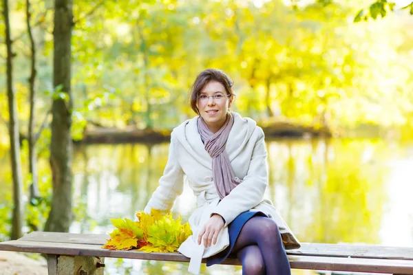 Mujer joven feliz con otoño de arce deja guirnalda en el parque . — Foto de Stock