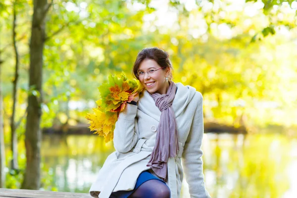 Glückliche junge Frau mit herbstlichem Ahornblätterkranz im Park. — Stockfoto