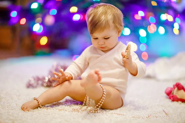 可爱的小女孩用可爱的手捧着五彩缤纷的灯饰.穿着节日服装和家人一起装饰圣诞树的小孩。传统假日的第一个庆祝活动是威赫纳腾节 — 图库照片