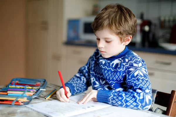 家庭で宿題をしている孤独な少年。屋内でカラフルな鉛筆で書く小さな子供。小学校と教育。コロナウイルスのパンデミックの封鎖中の家庭教育 — ストック写真