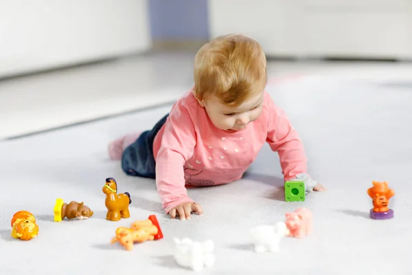 Adorable niña jugando con mascotas de juguete doméstico como vaca, caballo, oveja, perro y animales salvajes como jirafa, elefante y mono. Feliz niño sano divirtiéndose con coloridos juguetes diferentes en casa —  Fotos de Stock