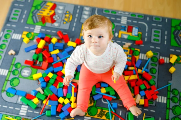 Schattig meisje dat met educatief speelgoed speelt. Gelukkig gezond kind hebben plezier met kleurrijke verschillende houten blokken thuis in de huiselijke kamer. Baby leren kleuren en vormen — Stockfoto