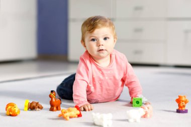 Sevimli bir bebek inek, at, koyun, köpek ve zürafa, fil ve maymun gibi vahşi hayvanlarla oynuyor. Mutlu sağlıklı çocuk evde renkli oyuncaklarla eğleniyor.