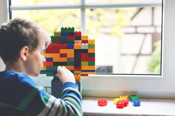 Petit garçon jouant avec beaucoup de blocs en plastique coloré. Adorable écolier s'amuser avec la construction et la création bâtiment par fenêtre. Technique créative de loisirs et robotique pendant le temps de couronne — Photo