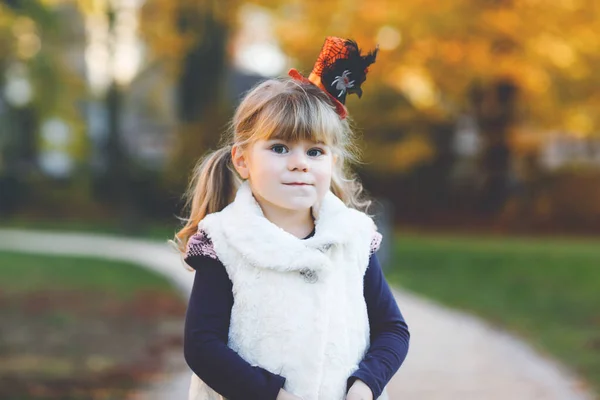 Portrét malé batolata dívka oblečené jako čarodějnice slaví Halloween. Šťastné dítě venku, s oranžovým legračním kloboukem na teplém podzimním dni. Krásná rodinná slavnostní sezóna v říjnu. Venkovní aktivita — Stock fotografie