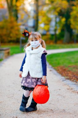 Küçük kız St. Martin alayı için el yapımı fener tutuyor. Çocuk tıbbi maske takıyor. Çocuklar ve aile geçidi anaokulunda. Alman geleneği Martinsumzug Salgını Corona virüsü karantinaya alındı