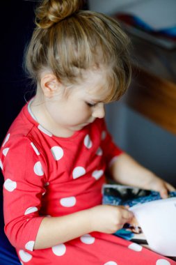 Moda dergisi ya da katalog okuyan küçük şık bir kız. Sevimli çocuk kıyafet seçerken eğleniyor..