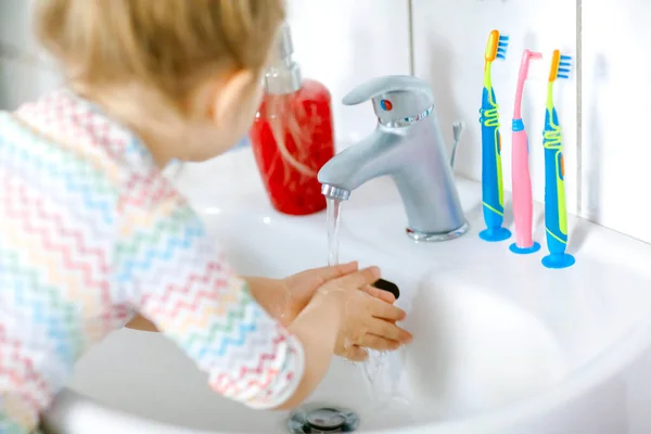 Egy kislányról, aki kezet mos szappannal és vízzel a fürdőszobában. Közelkép gyermek tanulás tisztító testrészek. Higiéniai rutineljárás vírusos megbetegedés esetén. gyerek otthon vagy óvoda. — Stock Fotó
