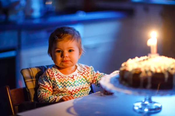 Cute beautiful little baby girl celebrating first birthday. Child blowing one candle on homemade baked cake, indoor. Birthday family party for lovely toddler child, beautiful daughter — Stock Photo, Image