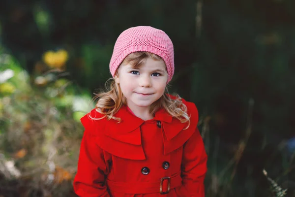 Linda niña pequeña en abrigo rojo haciendo un paseo a través del bosque de otoño. Feliz bebé sano disfrutando de caminar con los padres. Día de otoño soleado con el niño. Ocio activo y actividad con niños en la naturaleza. —  Fotos de Stock