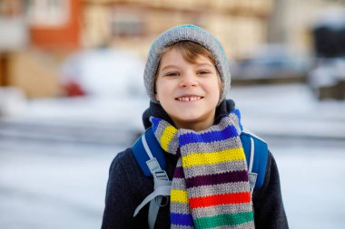 İlköğretim sınıfının küçük çocuğu kar yağarken okula yürüyor. Mutlu çocuk eğleniyor ve ilk karla oynuyor. Sırt çantalı öğrenci ya da renkli kış kıyafetleri içinde bir çanta..