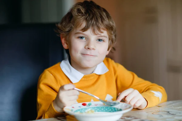 학교 남자 애 가 실내에서 야채 수프를 먹고 있어. 자녀를 부엌이나 학교 식당에 앉게 하 십시오. 귀여운 아이와 건강 한 음식, 국수, 닭고기, 야채가 들어 있는 유기농 야채 스프. — 스톡 사진