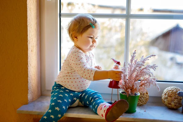 Joyeux adorable petite fille mignonne assise près de la fenêtre et regardant dehors sur la neige le jour de l'hiver ou du printemps — Photo