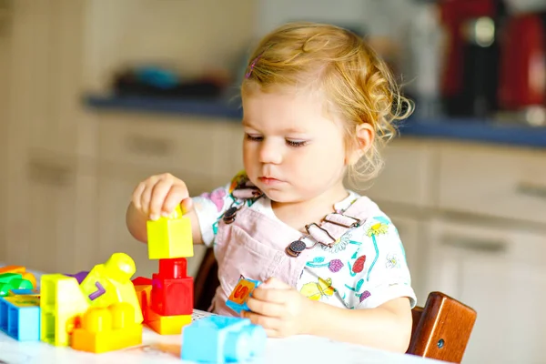Bebek odasında eğitici oyuncaklarla oynayan tatlı bir kız. Mutlu sağlıklı çocuk evde renkli farklı plastik bloklarla eğleniyor. Sevimli bebek öğrenimi yaratma ve inşa etme. — Stok fotoğraf