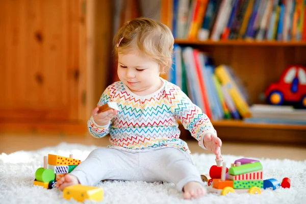 Liten flicka leker med pedagogiska träleksaker hemma eller på dagis. Småbarn med färgglada tåg. Barn som har roligt med olika leksaker. Ensam unge under koronaviruspandemisk karantän — Stockfoto