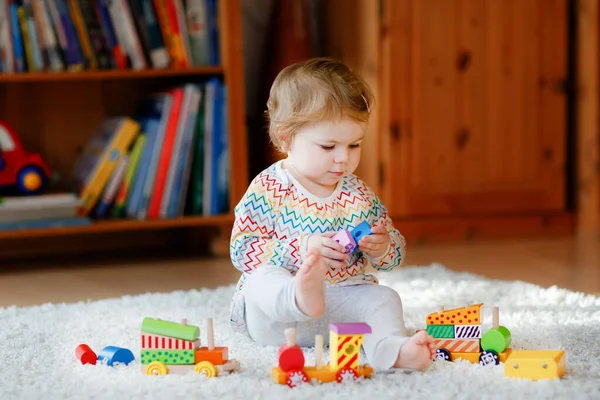 Niña jugando con juguetes educativos de madera en casa o en el vivero. Niño con tren colorido. Niño divirtiéndose con diferentes juguetes. Niño solitario durante la cuarentena pandémica del virus corona —  Fotos de Stock