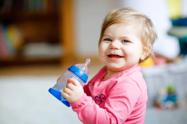 Linda niña adorable sosteniendo biberón y beber leche de fórmula o agua. Primera comida para bebés. Bebés sanos y concepto de alimentación con biberón para niños — Foto de Stock