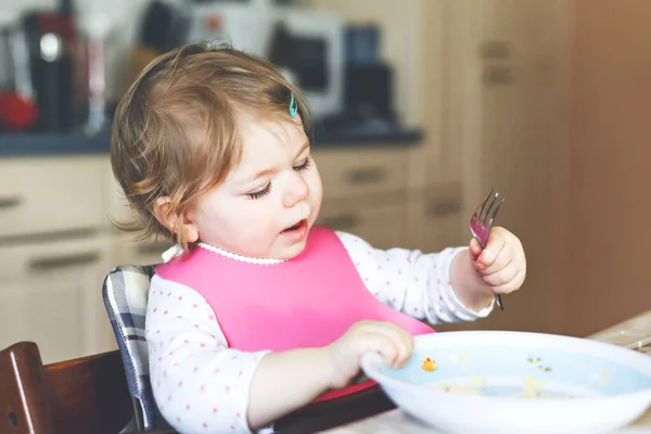 可爱的女婴用勺子、捣碎的蔬菜和浓汤吃饭。食物、儿童、食物和人的概念 — 图库照片