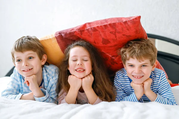 Three happy kids in pajamas celebrating pajama party. Preschool and school boys and girl having fun together — Stock Photo, Image