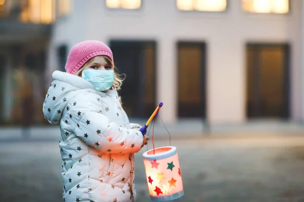 Дівчинка-малюк тримає саморобний ліхтар для процесії Святого Мартіна. Дитина носить медичну маску. Діти і сімейний парад у дитячому садку. Німецька традиція Вірус корони Мартінум. — стокове фото