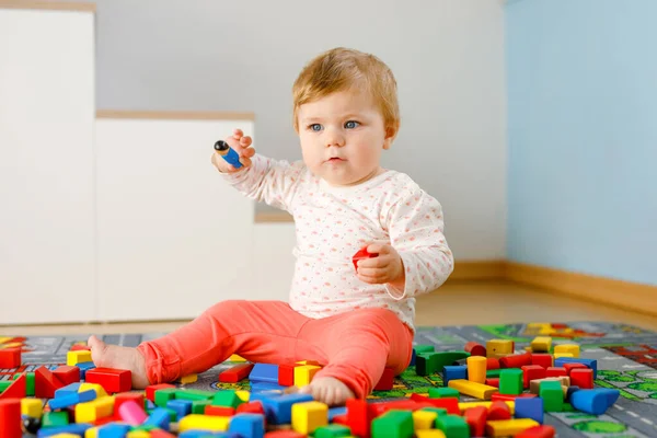 Schattig meisje dat met educatief speelgoed speelt. Gelukkig gezond kind hebben plezier met kleurrijke verschillende houten blokken thuis in de huiselijke kamer. Baby leren kleuren en vormen — Stockfoto