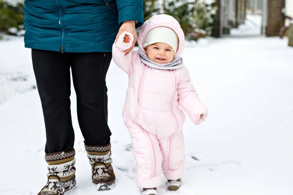 Adorable little baby girl making first steps outdoors in winter with mother. Cute toddler learning walking. — Stock Photo, Image