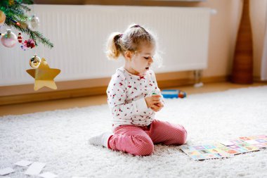 İki küçük çocuk, küçük tatlı kız ve okul çocuğu süslü Noel ağacında kağıt oynuyorlar. Mutlu sağlıklı kardeşler, erkek ve kız kardeşler birlikte eğleniyor. Aile Xmas kutlaması