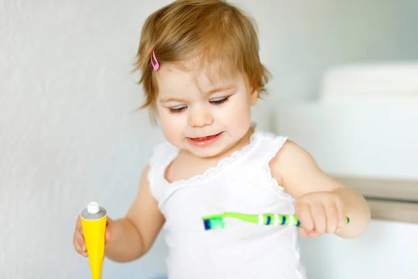 Niña sosteniendo cepillo de dientes y cepillándose los primeros dientes. Niños pequeños aprendiendo a limpiar los dientes de leche. — Foto de Stock