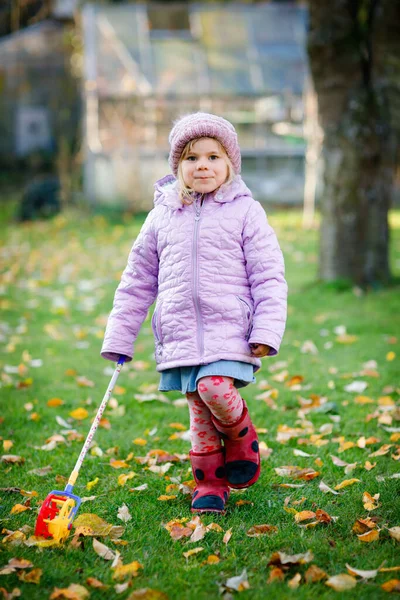 Pequena menina criança brincando no jardim de outono ou parque. Criança saudável feliz adorável se divertindo com brinquedo colorido. Criança em roupas de moda elegante, ao ar livre. — Fotografia de Stock