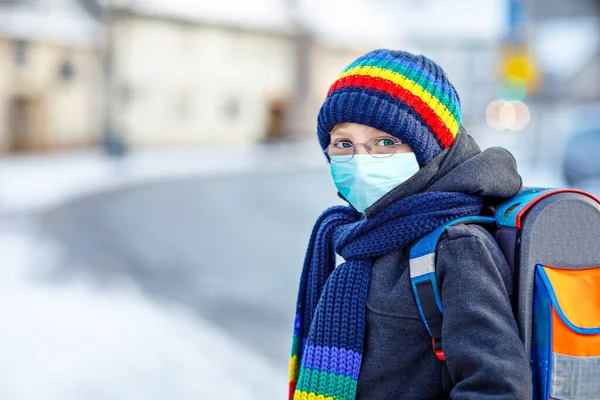 School kid boy with glasses wearing medical mask on the way to school. Child backpack satchel. Schoolkid on winter day with warm clothes. Lockdown and quarantine time during corona pandemic disease — Stock Photo, Image