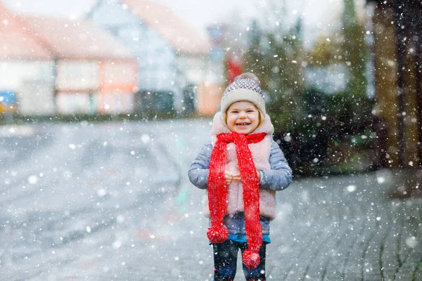 Cute little funny toddler girl in colorful winter fashion clothes having fun and playing with snow, outdoors during snowfall. Active outdoors leisure with children. Happy healthy child — Stock Photo, Image