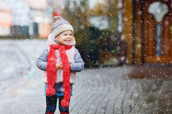 Petite fille drôle mignonne tout-petit dans des vêtements colorés de mode d'hiver s'amuser et jouer avec la neige, à l'extérieur pendant les chutes de neige. Loisirs en plein air actifs avec enfants. Heureux enfant en bonne santé — Photo