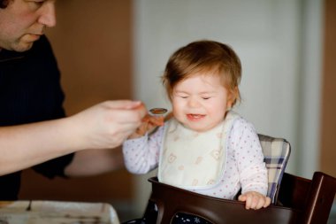 Babası bebeği kaşıkla sebze püresi ve püre püresinden besliyor. yemek, çocuk, beslenme ve insanların konsepti - tatlı bebek, kız ve baba sandalyede oturuyor ve evde yiyor.